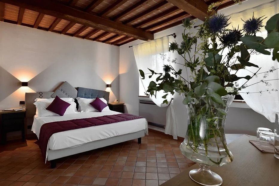 A spacious bedroom with beamed ceilings and fresh flowers