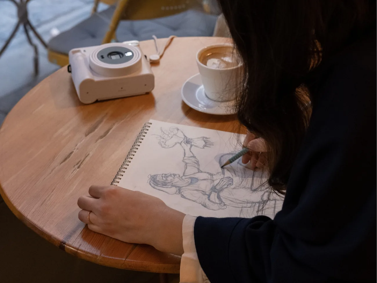 A woman sketching in her journal over a cappuccino