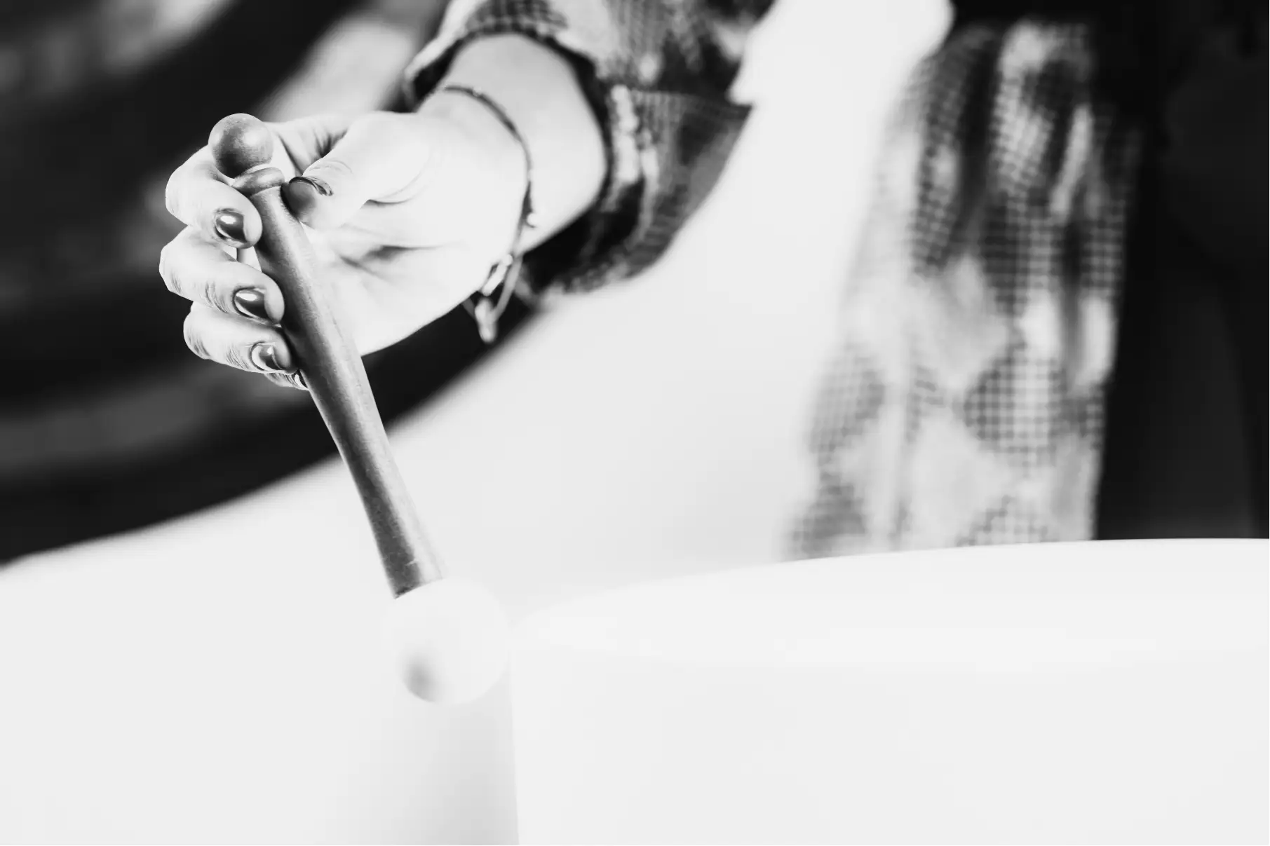 A hand striking a crystal singing bowl