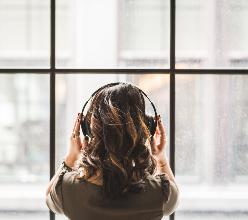 A woman listening with headphones by a window